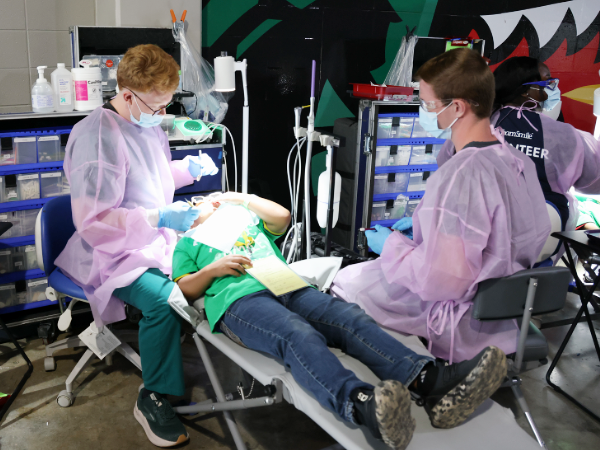 Two dental student volunteers working with child patient at UAB and TeamSmile event 2025