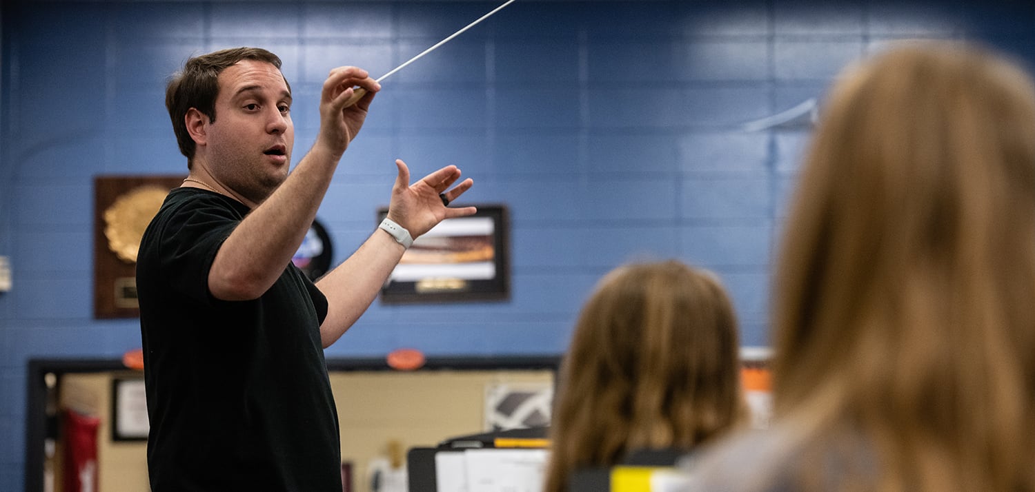 Photo of band director conducting music