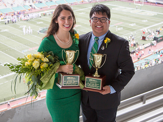 Photo of Yulianna Jimenez and Ryan Wong holding Mr. and Ms. UAB trophies - standing in front of football field.