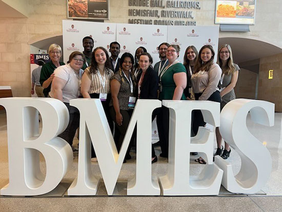 UAB undergraduate and graduate students posing behind a large cut-out BMES sign.