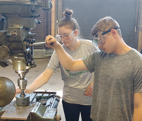 Jade Bustos and Dylan Cothron working with a drill press