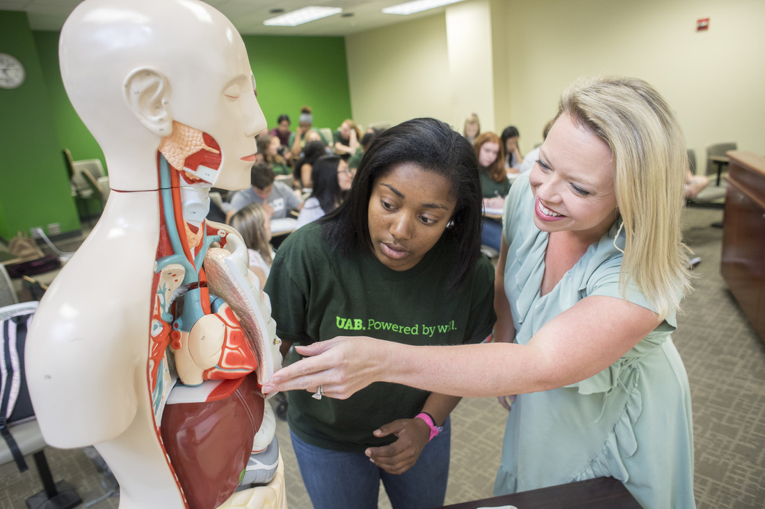Kristin Johnston Chapleau (Program Manager, Biomedical Sciences Program) talks to a student in a School of Health Professions classroom.