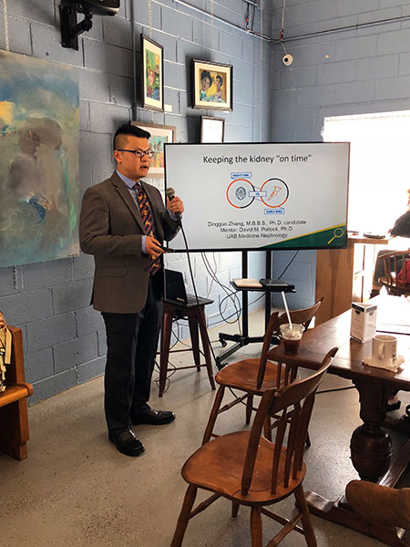 Student speaking to crowd while motioning towards slides. 