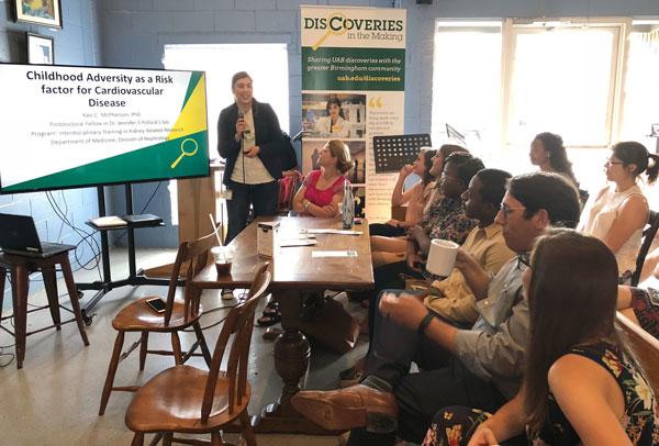 Crowd of students drinking coffee and listening to lecture.