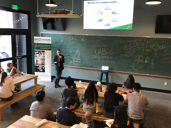 Daniel Kuhman presenting to a crowd of people.