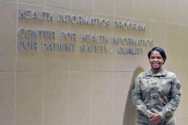 Jimmedda Mills standing in front of Health Informatics program sign.