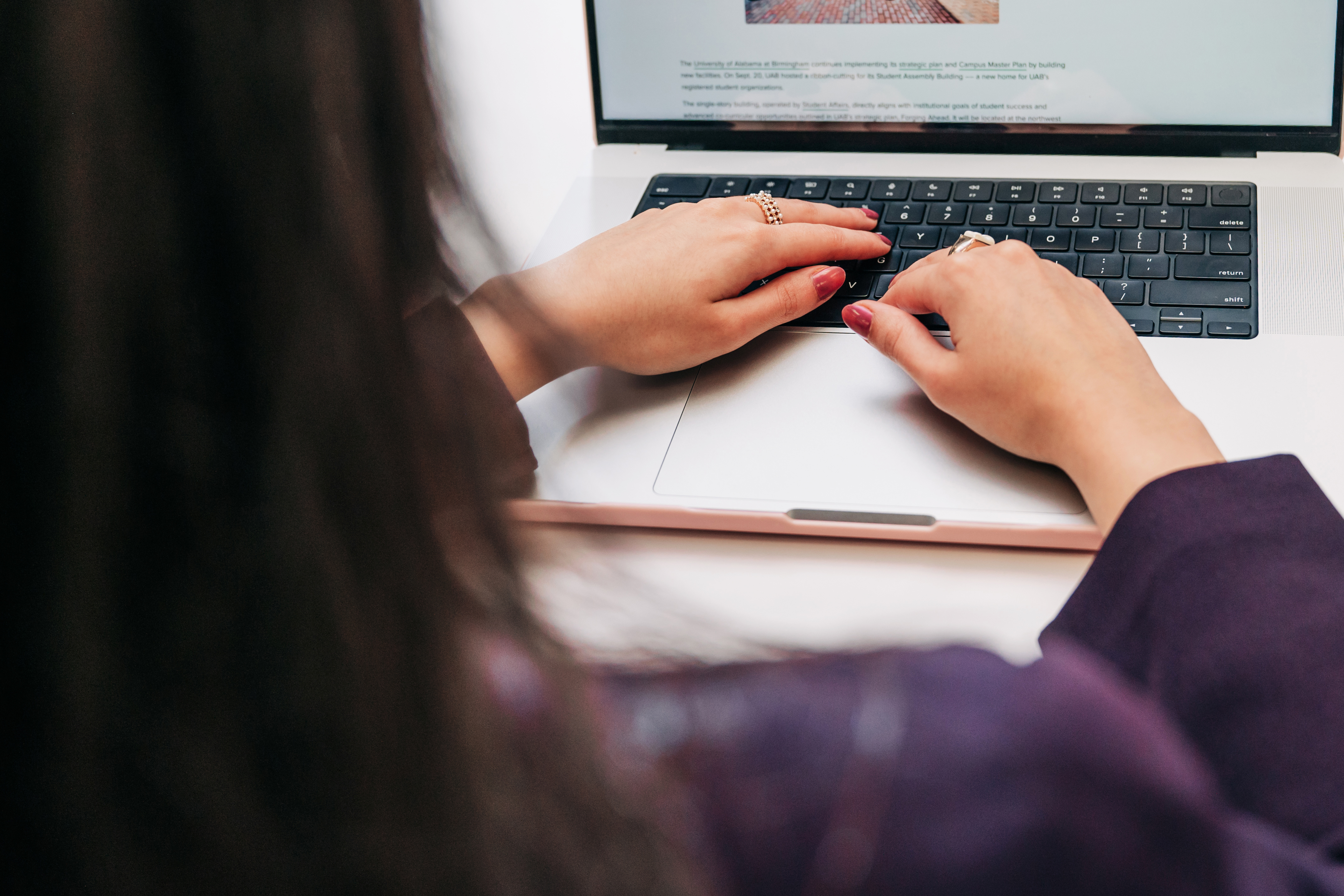 Hands of female UAB employee are typing on the keyboard of a laptop computer while she is sitting at a portable desk in office setting, September 2024.