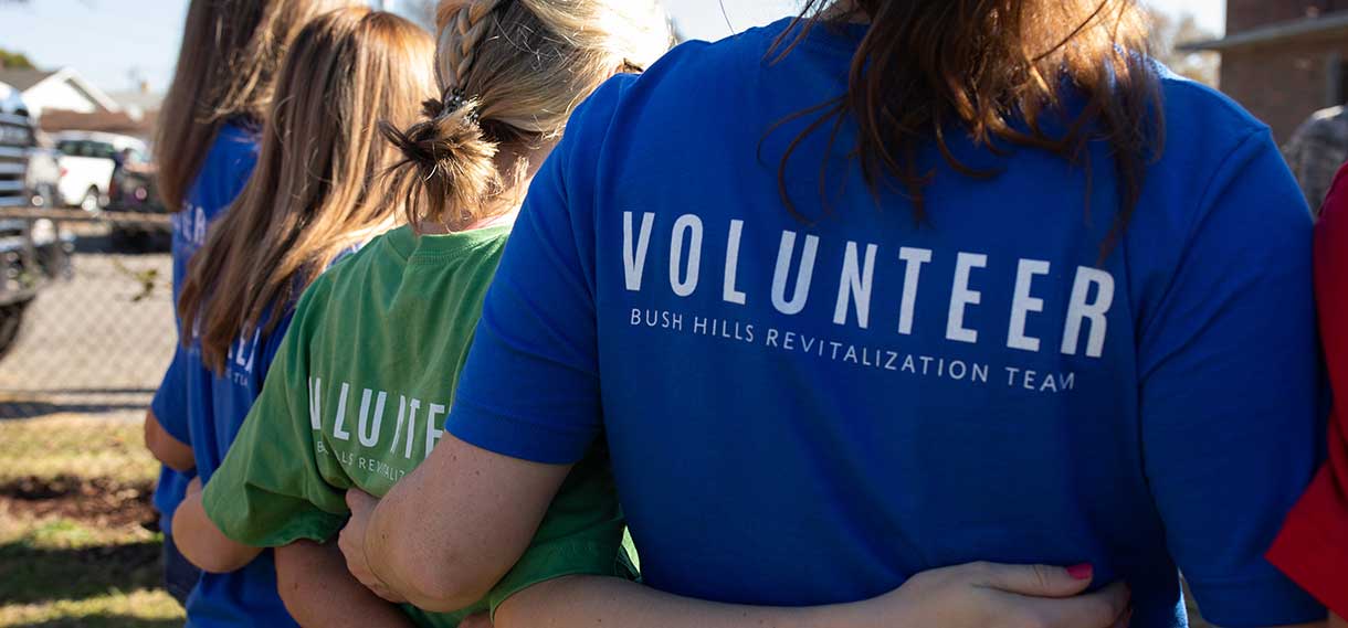 The backs of women wearing tshirts with "volunteer" written across the back.