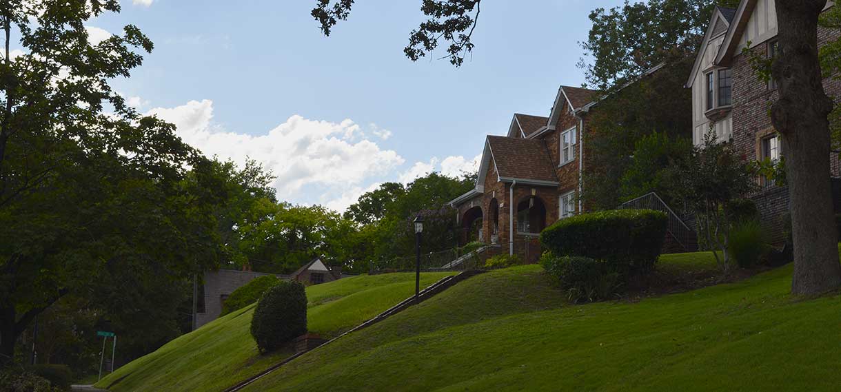 Houses with sloped, well-manicured lawns.