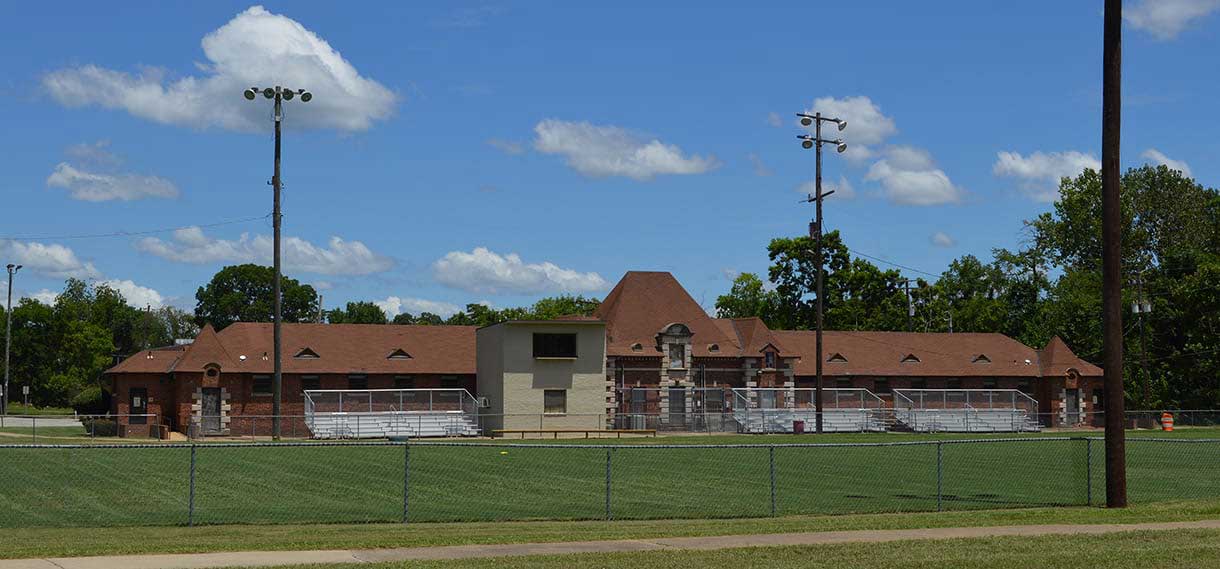 A building stretches behind a field with metal stadium benches.