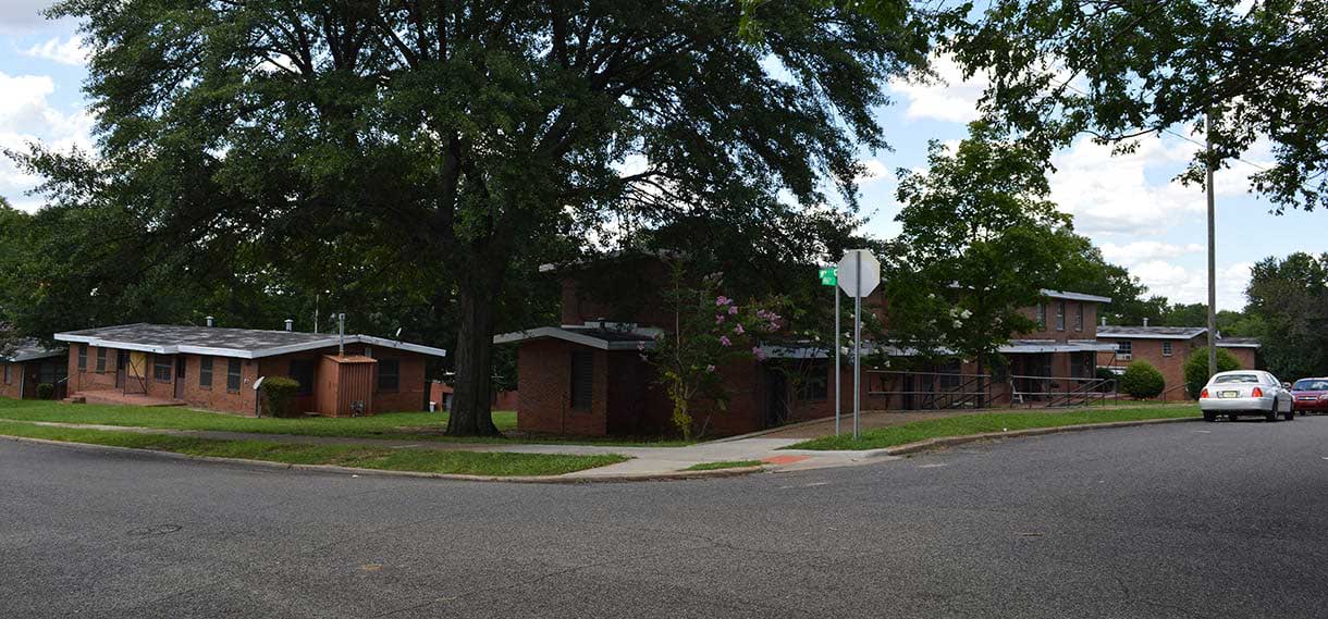 More brick buildings surrounded by large trees.