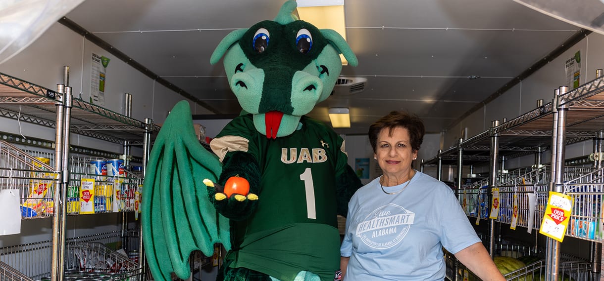 Dr. Fouad and Blaze stand in the mobile market - Blaze is holding out a red apple.