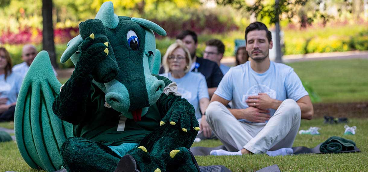 Blaze wipes his face with a towel while doing yoga outside with others.