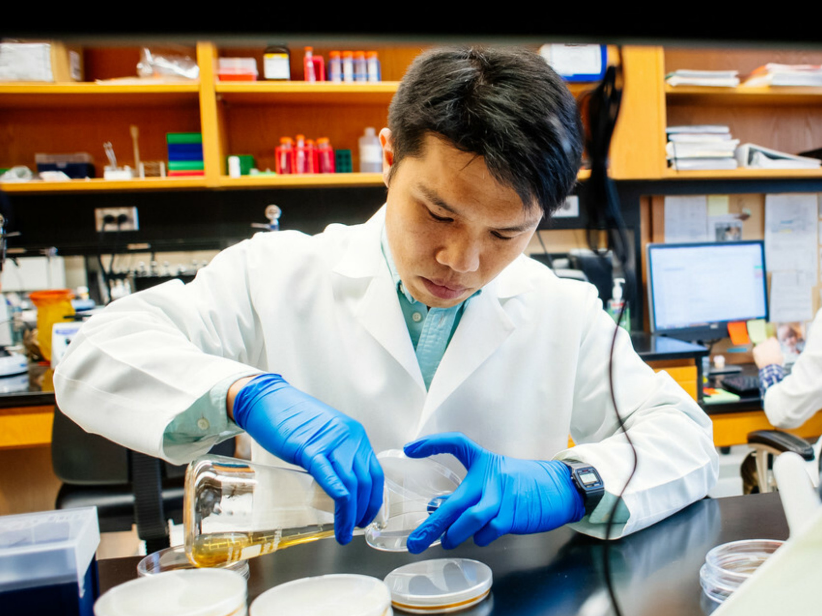 Brian Lu with beaker and petri dishes