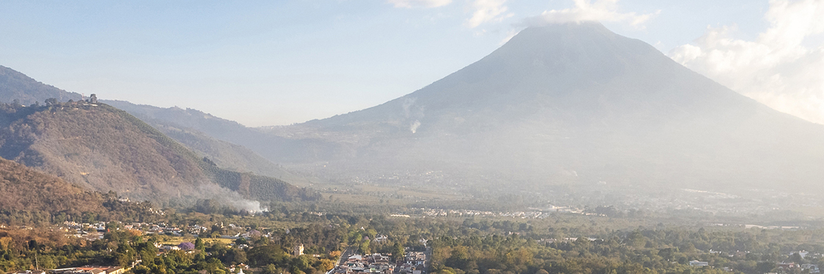 Image of the inactive Agua volcano, cobblestone streets, and colonial houses in Antigua Guatemala on a sunny day