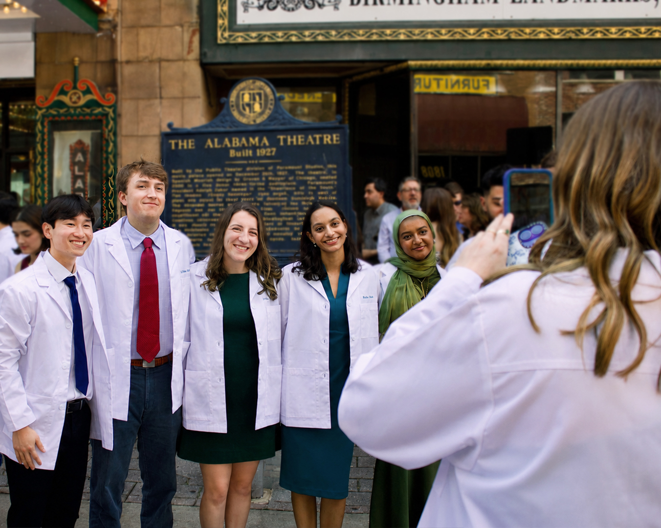 A group of Heersink School of Medicine residents taking a photo outside of Alabama Theater at the 2025 White Coat Ceremony.