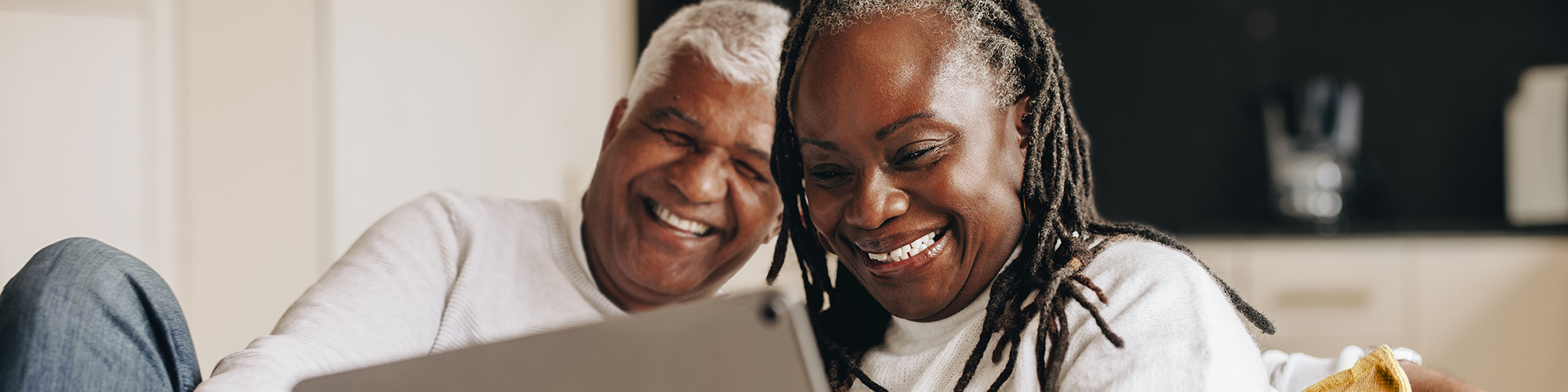 Happy senior couple smiling cheerfully while having a video call on a digital tablet. Senior couple communicating with their loved ones online. Mature couple enjoying their retirement at home.