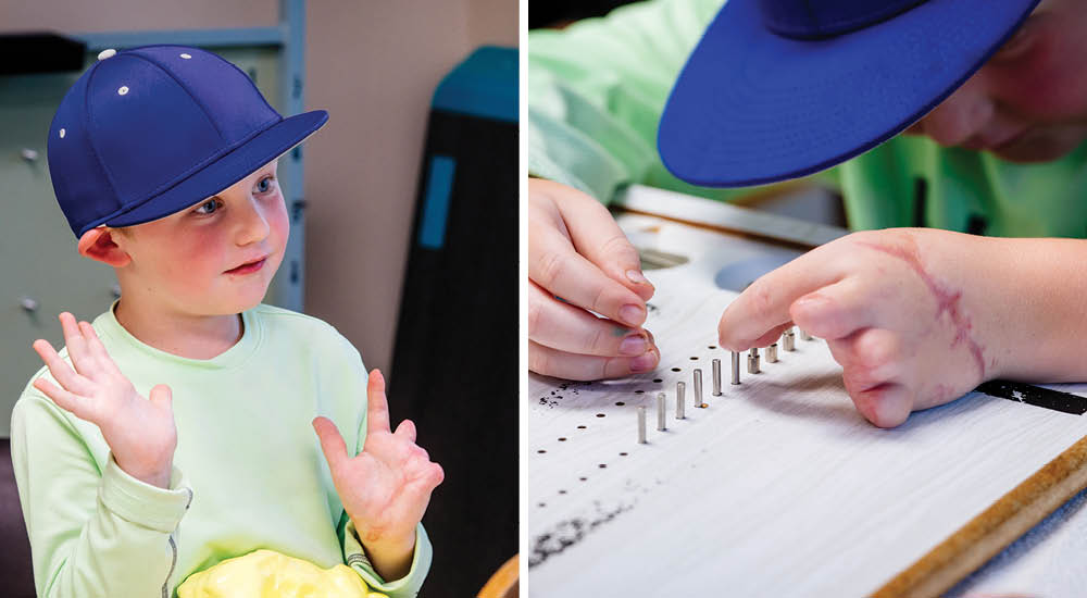 Young patient, Waylon, wearing a bright blue hat works with physical therapy tools to strengthen his hand. 