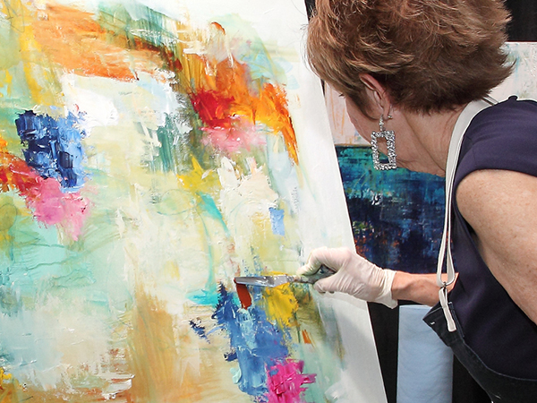An artist works on a colorful abstract canvas at the ArtBlink event.