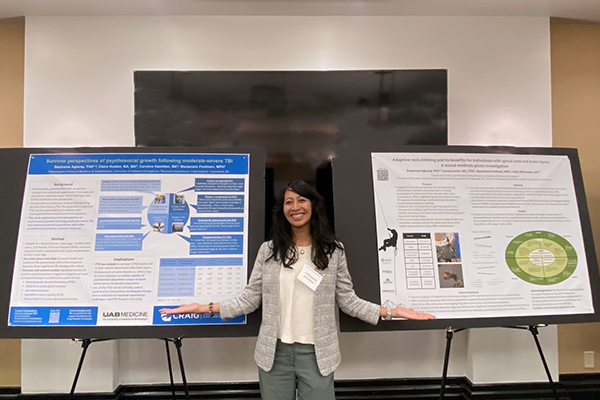 Associate Professor Stephanie Agtarap points to her two research posters at the Disability Health Symposium.