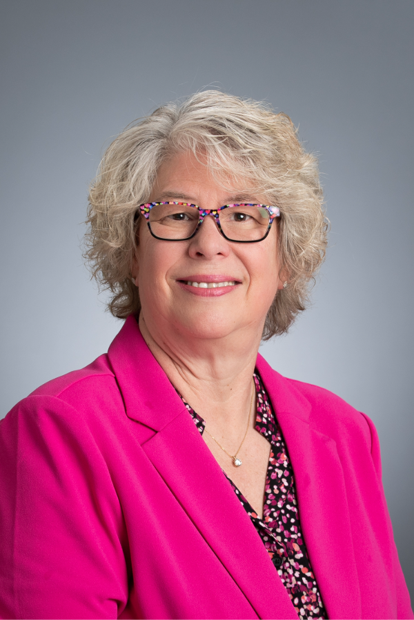 Barbara Van Der Pol, Ph.D., stands in front of a gray background.