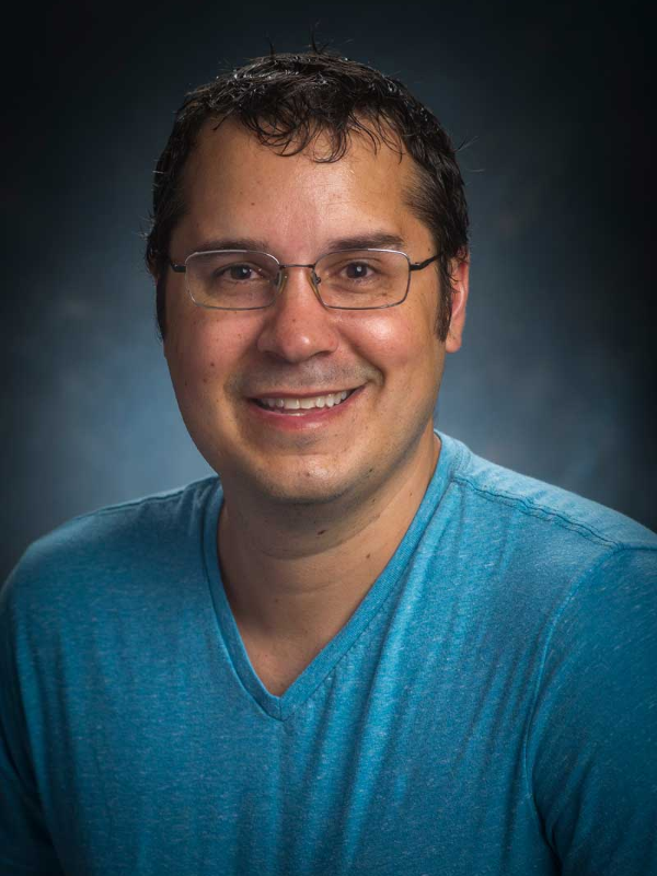 Jeremy Foote, Ph.D., stands in front of a blue background.