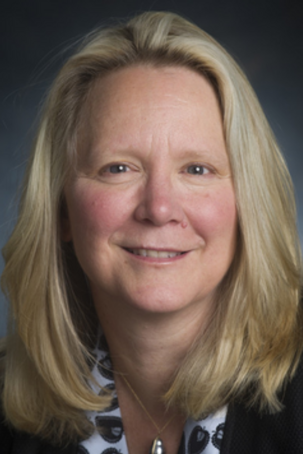 Frances Lund, Ph.D., standing in front of a blue textured background.