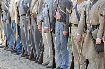 Reinactors in blue and gray civil war uniforms - photo shows them only from the shoulders down. 