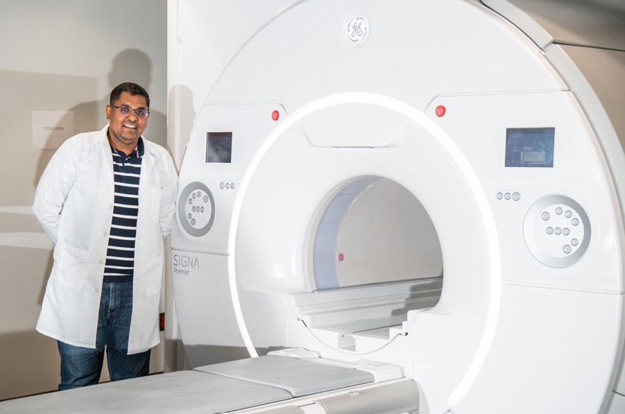 Dr. Virendra Mishra, PhD (Associate Professor, Radiology is standing next to GE Healthcare SIGNA Premier 3T Wide-Bore MRI scanner at UAB Highlands, October 2024.