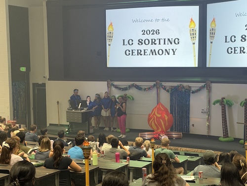Orientation Leaders speak from podium on auditorium stage.
