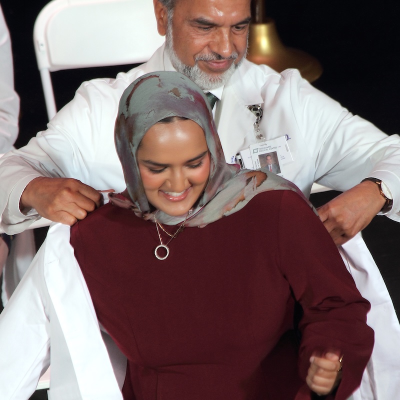 Medical student putting on white coat on stage.