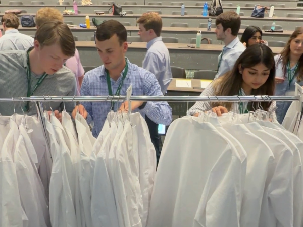 Medical students browse through new physician white coats.