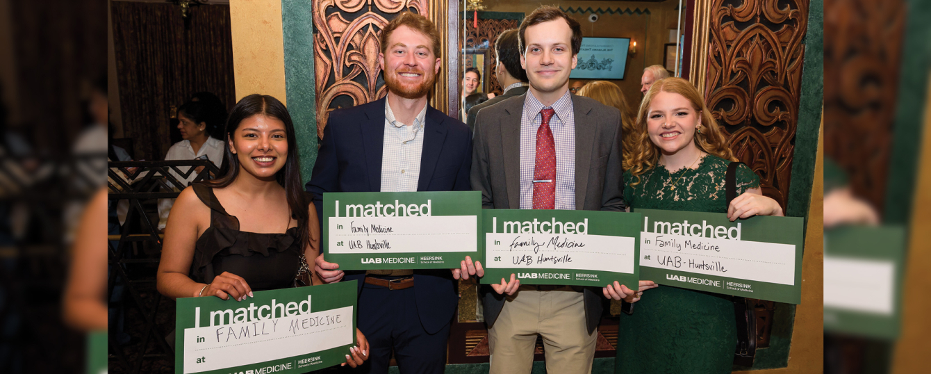 Four medical students stand together holding green UAB Medicine Match Day signs, each sign indicates a match in Family Medicine, with three signs listing UAB Huntsville as the residency location.