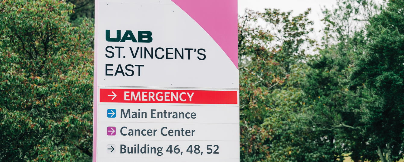 Close-up of roadside signage that reads "UAB St. Vincent's East" with small trees in background, November 1, 2024.