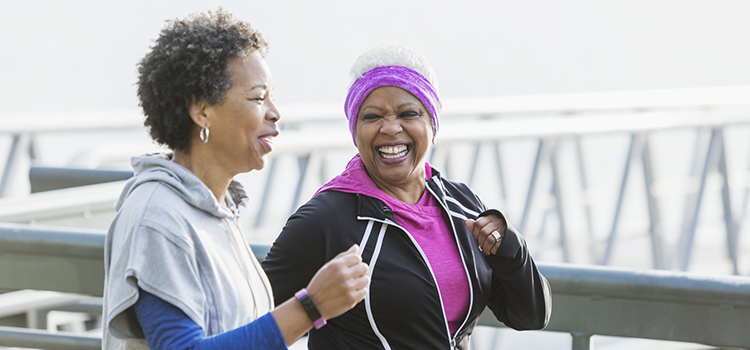 Two African-American women exercising together wearing fitness tracker.