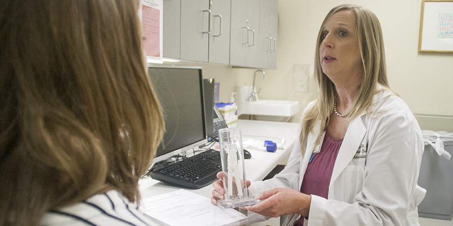 Nurse Research Manager Rebecca St. John shows a device model to a potential clinical trial subject.