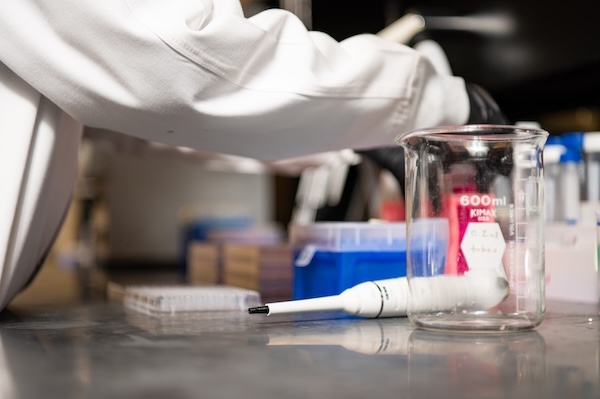 Arm of lab worker is working over a pipette and specialized lab tray in a Hematology and Oncology research lab.