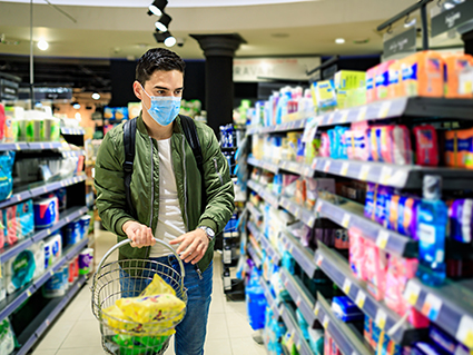 Concept, diseases, viruses, allergies, air pollution. Portrait of a young man wearing a protective mask in a store and looking for a disinfectant. The face of a young man wearing a mask to prevent germs, toxic fumes and dust. Prevention of bacterial infection with Corone or Covid 19 virus in the air around streets and gardens.