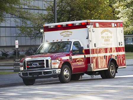 UAB and the Birmingham Fire Department conduct an Ebola drill at The Kirklin Clinic and the UAB Emergency Department involving first-responders dressing out in PPEs to transport a simulated patient, 2014. Birmingham Fire and Rescue Service truck parked on street.