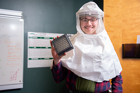Joseph Moore of UAB Engineering, holding a prototype of the filter reservoir, wears a hood during a fit test for a 3d printed filter reservoir that he designed and created for ventilators
