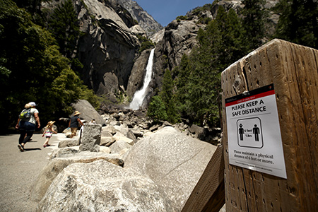 YOSEMITE NATIONAL PARK, CALIFORNIA - JUNE 11: A sign explaining social distancing at Yosemite Falls on June 11, 2020 in Yosemite National Park, California. . Yosemite National Park reopened today with many restrictions after shutting down in March to protect people from COVID-19. Only about half of the average June visitors will be allowed in, and they must make an online reservation for each car. The park will issue 1,700 day passes each day and an additional 1,900 passes for reservations at campsites or hotels in the park. (Photo by Ezra Shaw/Getty Images)