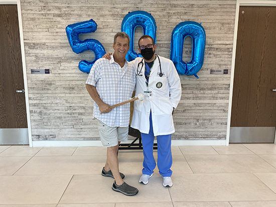 Patient and doctor standing in front of balloons that spell out 500