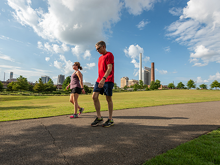 Couple is walking on paved trail in Railroad Park.