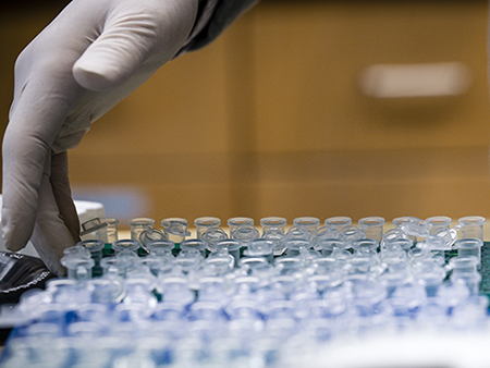 Close-up of gloved hands picking up tray of pipettes in the Comprehensive Genomics Shared Facility cancer research laboratory directed by Dr. Michael Crowley, PhD (Associate Professor, Genetics Research; Co-Director, CGSF) and Dr. Shawn Levy, PhD (Adjunct Professor, Epidemiology; Co-Director, CGSF), 2019.