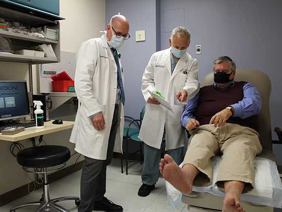 Two doctors looking at patient's foot. 