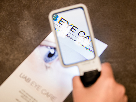 Patient using the Mobilux - pocket magnifier with light - to read brochure. 