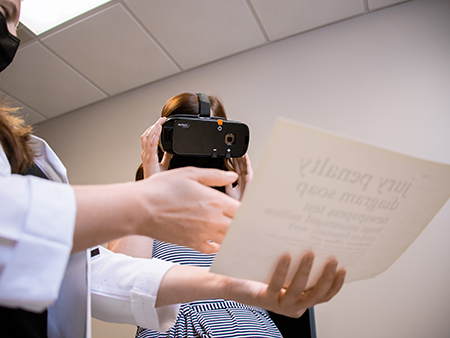 Patient using the Patriot - a head mounted electronic video magnifier - to read piece of paper. 