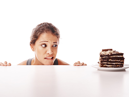 Studio shot of a young woman looking at a piece of cake.