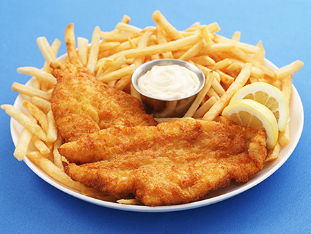 Full-frame, high-resolution digital capture of a plate of delicious, crispy fried fish and chips with a metal ramekin of tartar sauce. Plate sits on a blue surface, and is garnished with lemon slices.