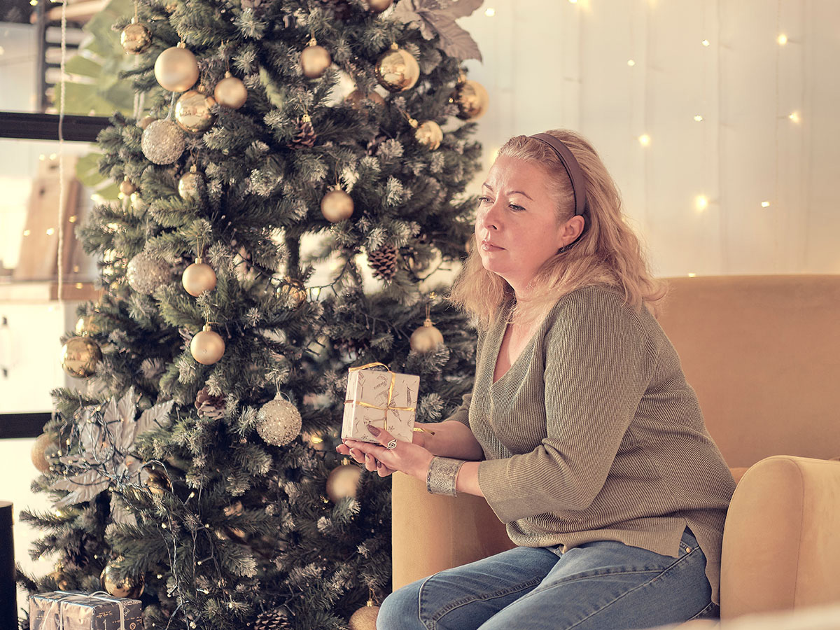 Woman sitting sadly beside a Christmas tree